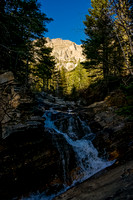Bertha Peak rises in the morning sun behind a waterfall on the creek that cascades out of Bertha Lake
