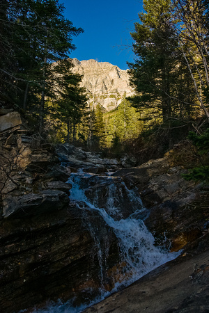 Bertha Peak rises in the morning sun behind a waterfall on the creek that cascades out of Bertha Lake