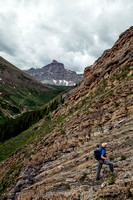 Keith ascending the stepped terrain with Castle Peak in the background.