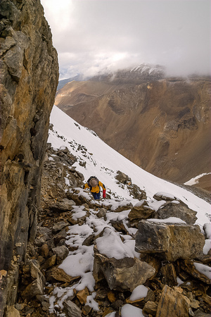 Under thick cloud, Bob scrambles up through the rubble and cliff bands on Kiwetinok Peak.
