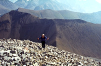 Kev comes up to the summit on classic Rockies scree with Grizzly and Highwood Ridge in the background.