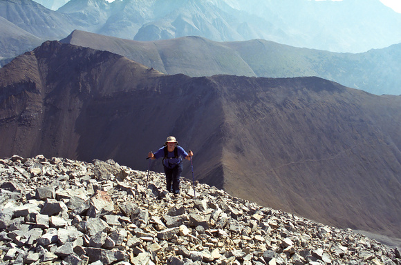 Kev comes up to the summit on classic Rockies scree with Grizzly and Highwood Ridge in the background.