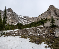The cairn at the edge of the boulder field just visible at center and the open terrain leading to the alpine bowl ahead. Sentinel towers at right and Elliott at left.