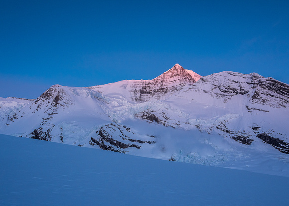Mount Robson catches alpine glow as an ice avalanche thunders down the Robson Cirque in the foreground!