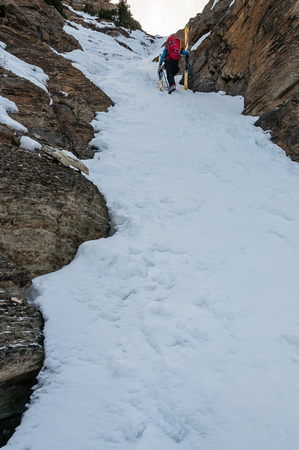TJ carries his skis up the waterfall through the headwall.