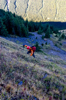 Raf climbs the steep grass slopes that lead up to the brown, dirt pinnacle.